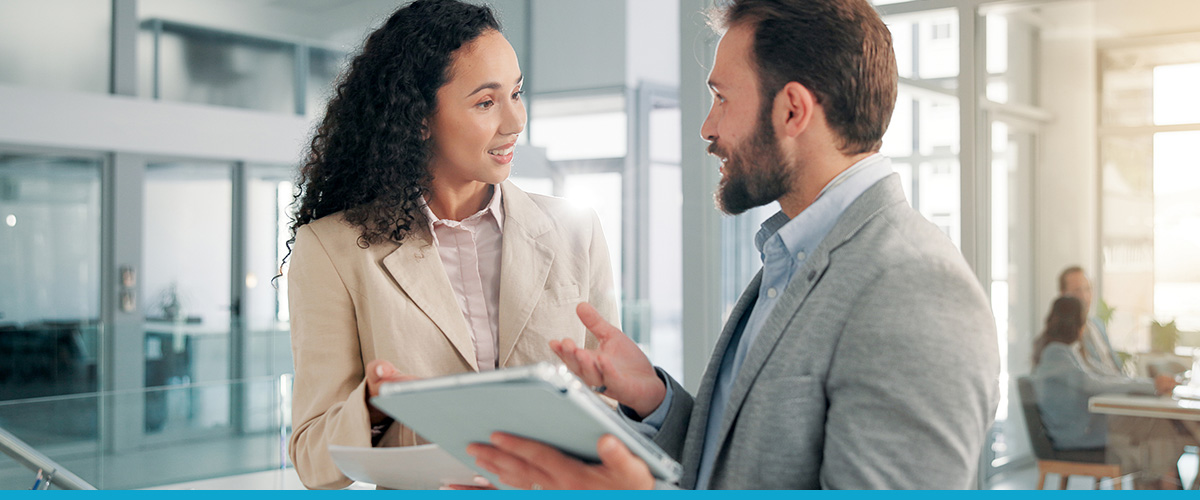Two people in professional dress talking with folders in hand
